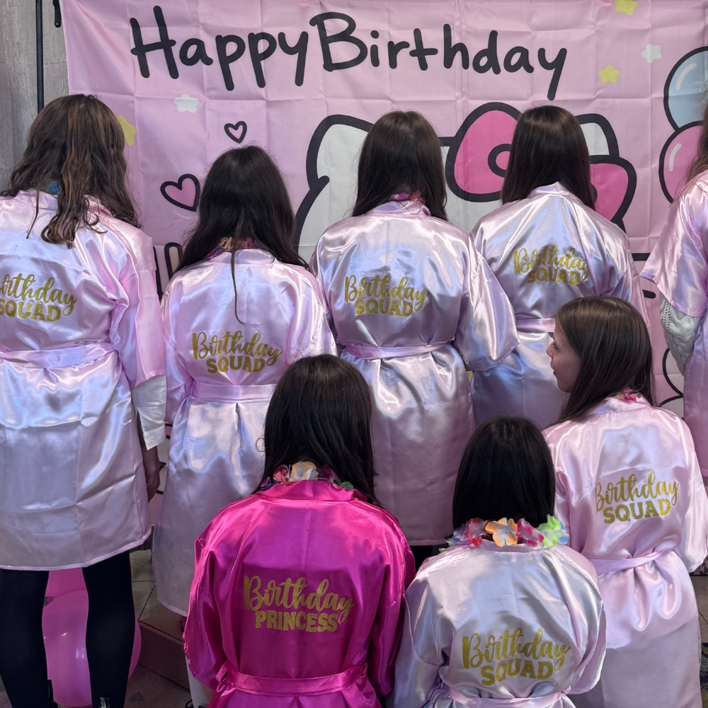 Bambine con vestaglie Birthday Squad davanti allo sfondo Hello Kitty